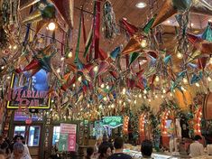 many colorful streamers hang from the ceiling above a bar in a restaurant with people sitting at tables