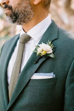 a man wearing a suit and tie with a boutonniere on his lapel