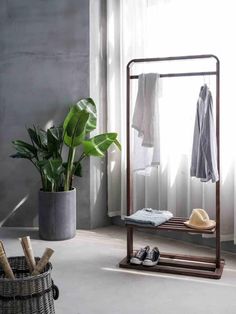 a room with a mirror, clothes rack and shoes on the floor next to a window