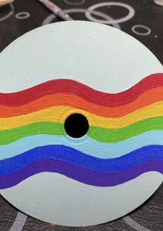 a white painted disc with multicolored lines on it and scissors in the background