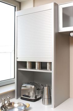 a kitchen counter with a microwave, toaster and coffee pot on it in front of a window