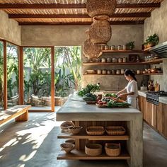 a woman standing in a kitchen next to a counter filled with fruits and veggies