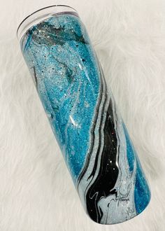 a blue and black marbled drink cup sitting on top of a white fur covered floor