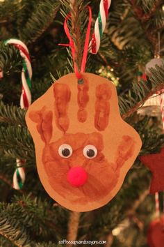 a handprinted ornament hanging from a christmas tree with candy canes