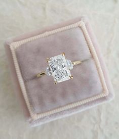 an engagement ring in a velvet box on top of a white carpeted tablecloth