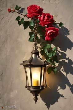 a light that is on the side of a wall with flowers growing out of it