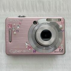 a pink camera sitting on top of a white blanket