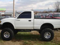 a white pick up truck parked in a parking lot next to other cars and trucks