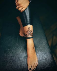 a woman's foot with a tattoo on her left leg and black leather pants