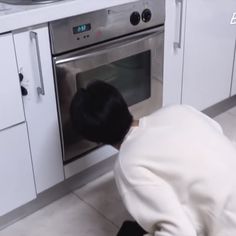 a person bending over to look into an oven