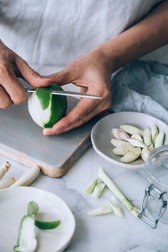 a person cutting up an onion on top of a cutting board next to other food items