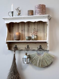 a shelf with candles, vases and other items hanging on it's sides