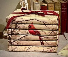 a stack of folded books with a red bird on the cover and ribbon tied around it