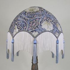 an ornate blue and white lamp shade with tassels on the sides, hanging from a wall