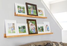 the family photos are hung on the wall above the couch and below the stairs in the living room