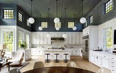 a large kitchen with lots of white cabinets and counter tops, along with an oval dining table