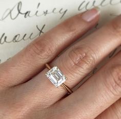 a close up of a person's hand with a diamond ring on their finger