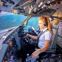 a female pilot is sitting in the cockpit of an airplane with her headphones on