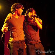 two men standing next to each other on stage with microphones in their hands,