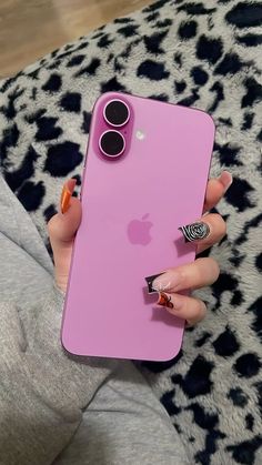 a woman's hand holding an iphone in front of her pink case with black and white designs