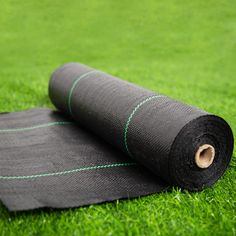 rolled up yoga mat laying on the grass with green line around it and two rolls of black fabric