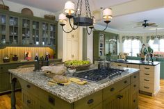 a large kitchen with green cabinets and marble counter tops