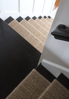 a black and beige carpeted stair tread next to a white door