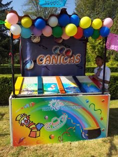 an ice cream stand with balloons and candy on display for kids to play in the park