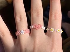 a woman's hand with two rings on it, one has flowers and the other has daisies