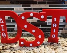 the letters are made out of red plastic and have white pearls on them, along with numbers that read dst