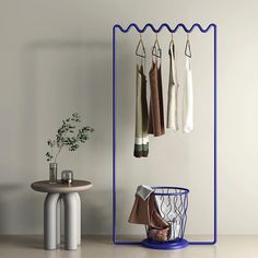 clothes hanging on hooks in a room with a round table and small stool next to it