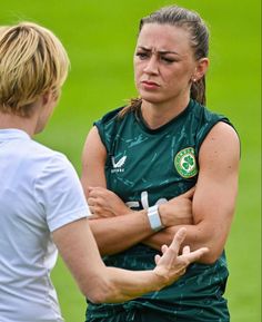 two women standing next to each other on a soccer field