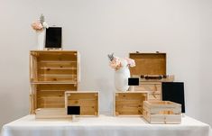 a table topped with lots of wooden boxes and vases filled with flowers on top of it