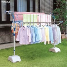 clothes are hung on the clothesline in front of an apartment building with grass and trees