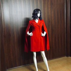 a mannequin dressed in a red coat stands next to a wood paneled wall