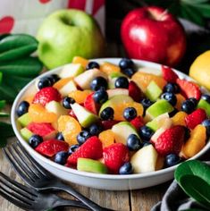 a white bowl filled with fruit on top of a wooden table