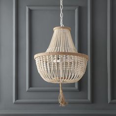 a white chandelier hanging from the ceiling in a room with gray walls and wood paneling