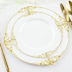 a white plate topped with gold colored utensils next to a fork and knife