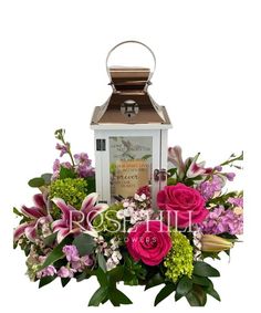 a white lantern with pink flowers and greenery in front of it on a white background