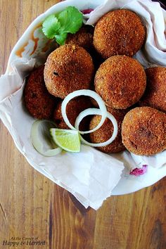 some food that is sitting on a plate with onion rings and cilantro wedges