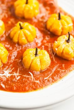 small pumpkins are placed on top of tomato sauce