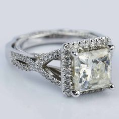 an engagement ring with a princess cut diamond surrounded by pave and round brilliant diamonds