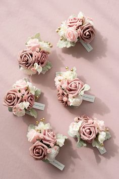 pink and white flowers are arranged on a pink surface with tags attached to the hair pins