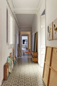 an empty hallway with paintings on the wall and wooden furniture in the foregrounds