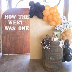 a wine barrel with balloons on it next to a sign that says how the west was one