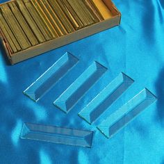 three pieces of clear glass sitting on top of a blue cloth next to a wooden box