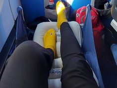 someone is sitting in an airplane with their feet on the seat and there are many bags behind them