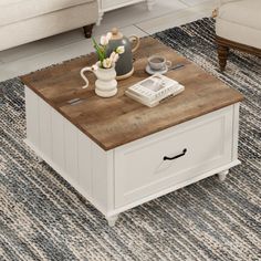 a living room with a couch, coffee table and rug on the floor in front of it