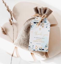 a white chair with a blue and gold floral design on it's back, next to a burlap bag that says thank you