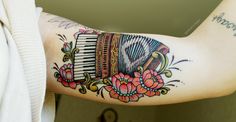 a person with a tattoo on their arm holding a musical instrument in front of them